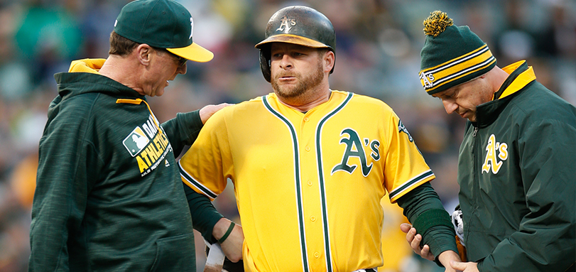 A?s head trainer Nick Paparesta '94 (right) examines the hand of Stephen Vogt (center) while manager Bob Melvin (left) looks on.